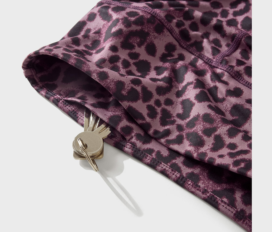 Nahaufnahme einer lila-schwarzen Leggings mit Leopardenmuster, aus deren Tasche ein Schlüsselbund hängt.