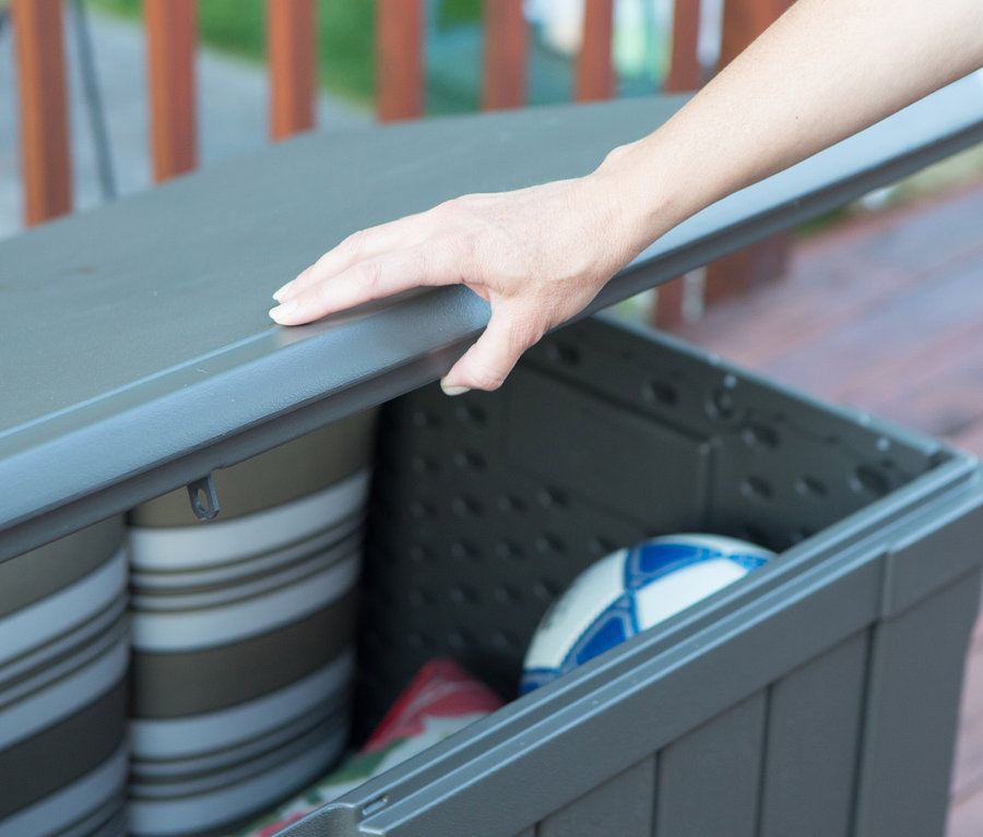 Hand öffnet graue Lifetime-Kissenbox, ca. 440 l, gefüllt mit Kissen und Fußball.