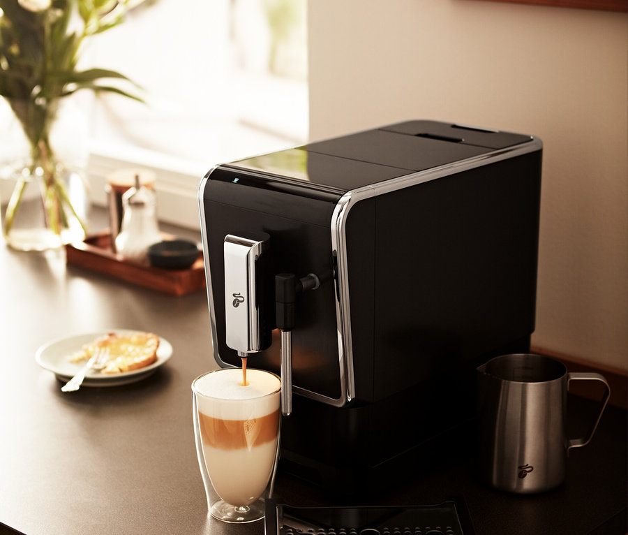 Tchibo »Esperto Latte« Kaffeevollautomat, Anthrazit bereitet Getränk in einem Glas zu.