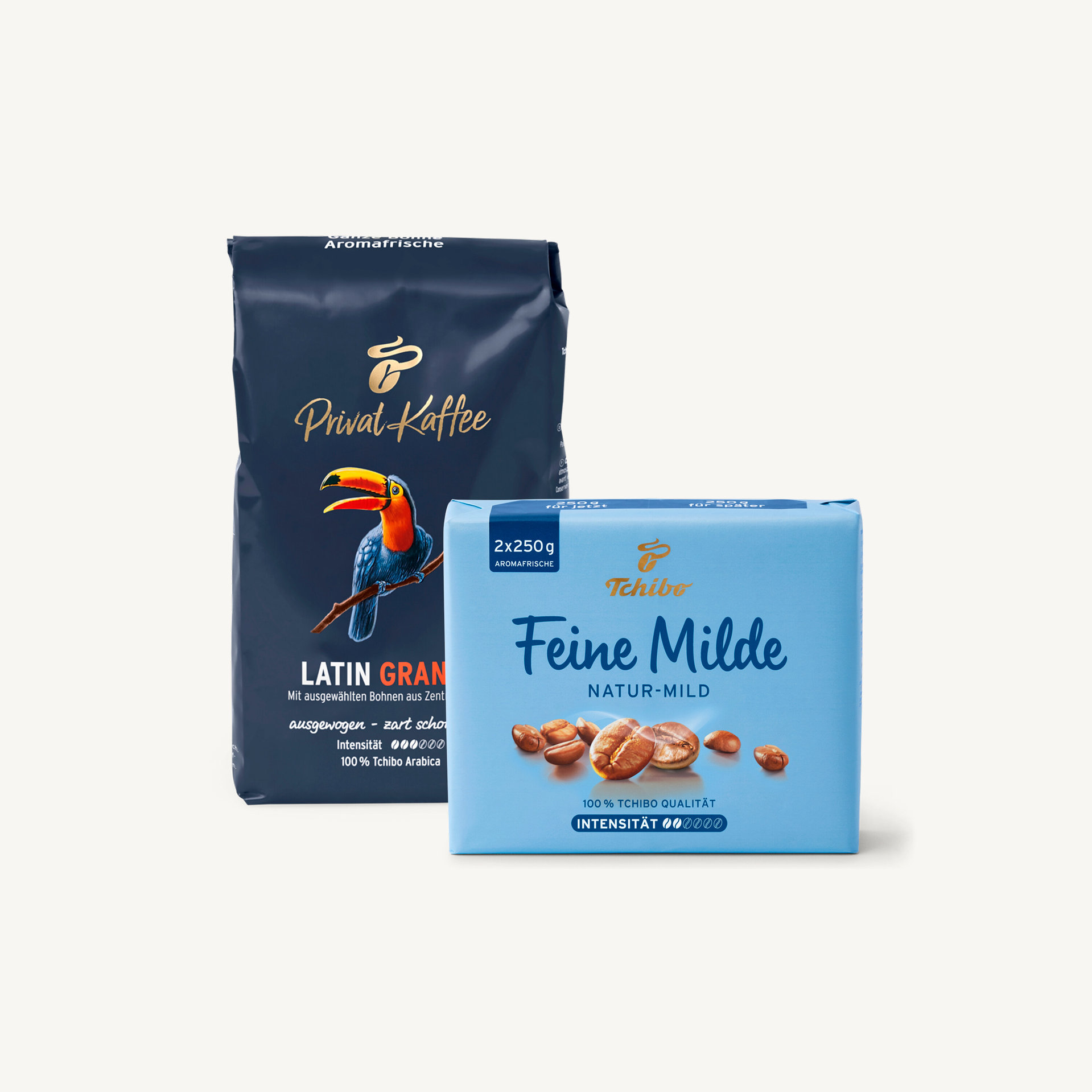 Eine dunkelblaue Packung Privat Kaffee Latin Gran Kaffeebohnen mit einem Tukan neben einer hellblauen Packung Tchibo Feine Milde gemahlenem Kaffee.