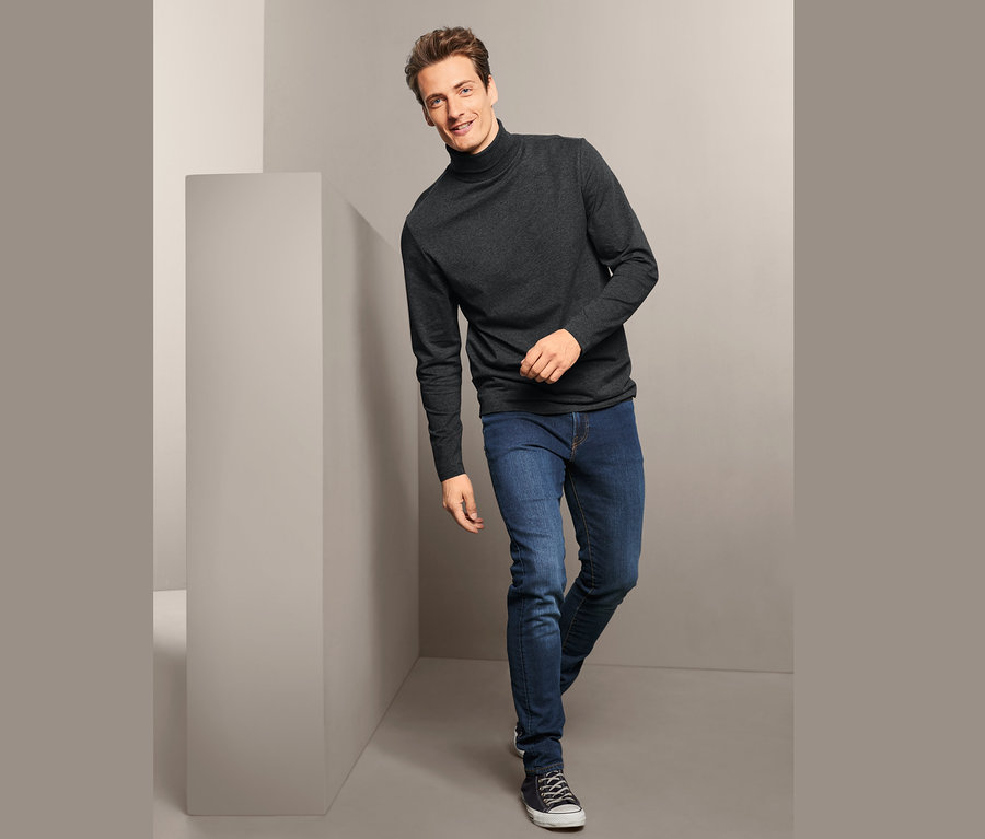 Mann posiert in einem grauen Rollkragenshirt von 2 Rollkragenshirts und Jeans.