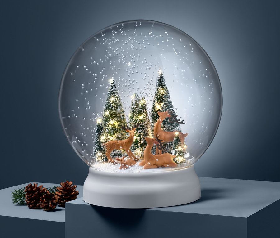 Eine LED-Outdoor-Schneekugel mit Rehfiguren und Bäumen auf blauem Hintergrund.