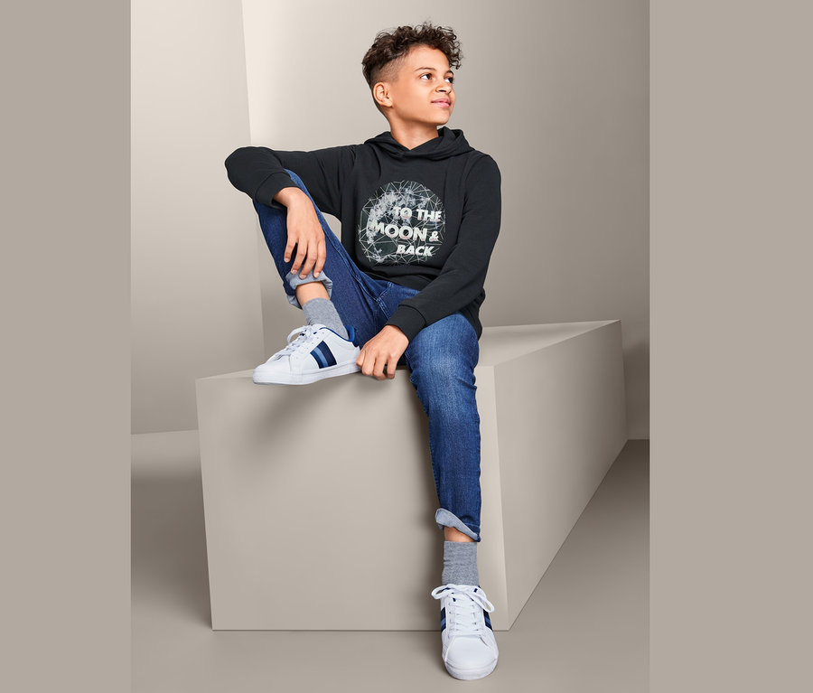 Ein Junge sitzt und trägt ein Sweatshirt.