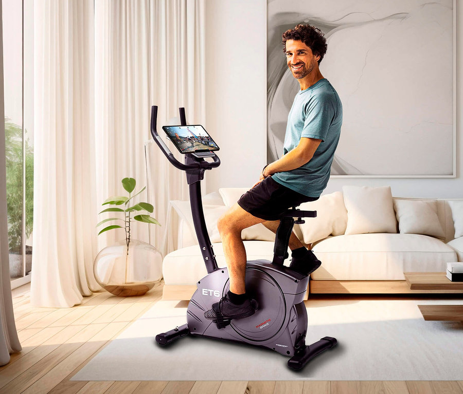 Mann sitzt auf Christopeit Sport Heimtrainer Ergometer »ET 6« im Wohnzimmer.