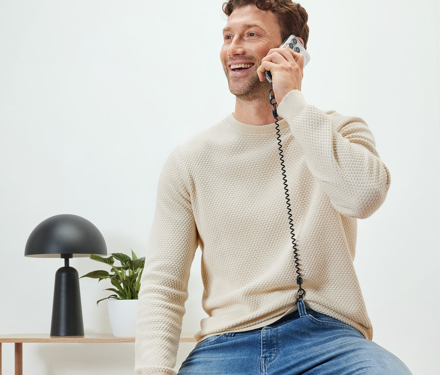 Mann sitzt und telefoniert mit Handy-Sicherheitskette.