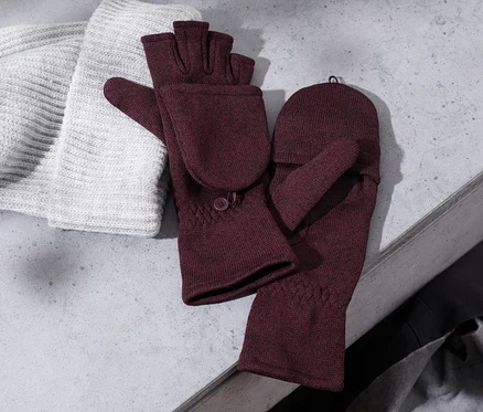 Eine Strickmütze liegt neben bordeauxfarbenen Strickfleece-Klappfäustlingen.