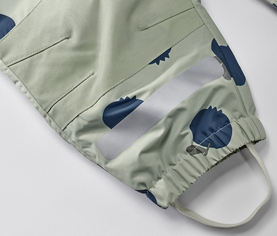 Detailansicht eines Kleinkind-Regen-Einteilers mit Blaubeermuster, reflektierendem Streifen und elastischem Saum.