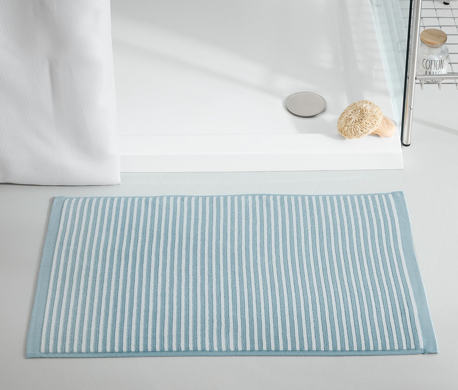 Blauer Duschvorleger liegt vor der Duschkabine.