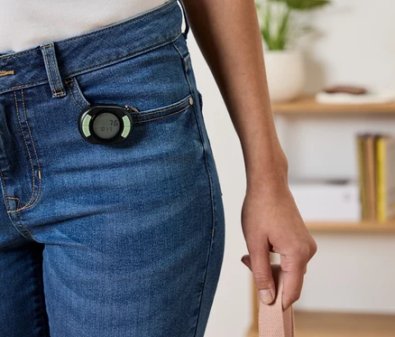 Schwarzer Schrittzähler an der Vordertasche einer blauen Jeans befestigt.
