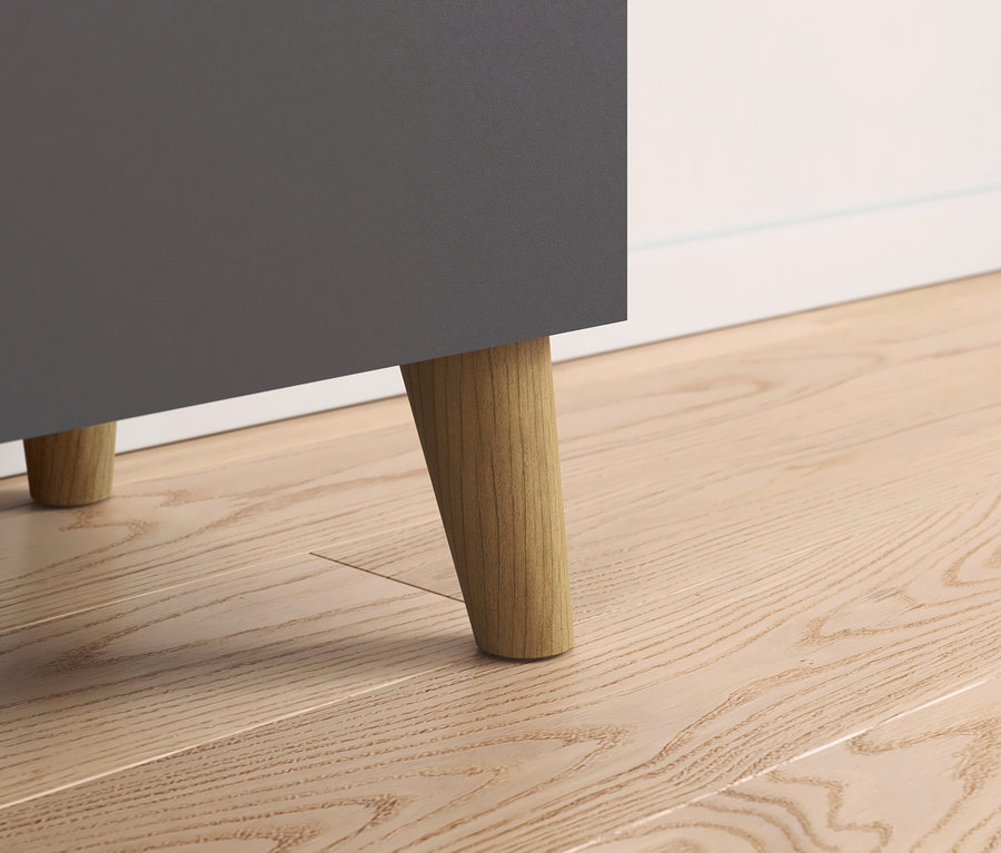Detailaufnahme eines grauen Schranks mit Holzfüßen auf einem Holzboden.