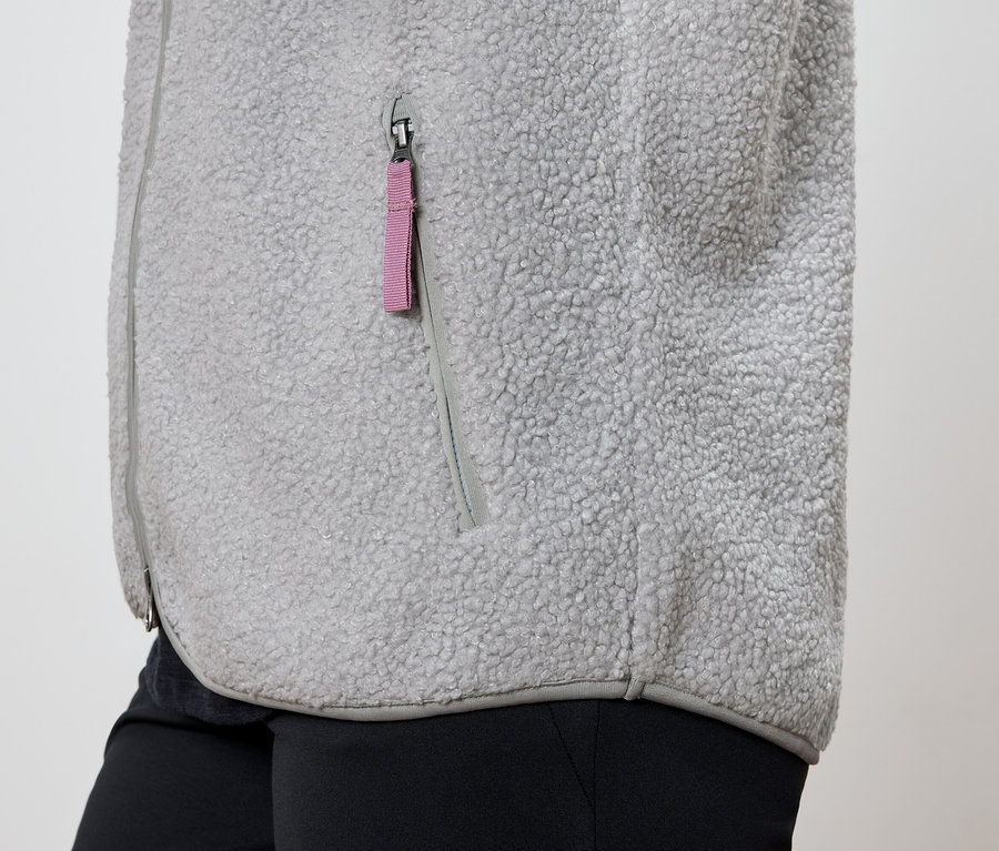 Detail einer grauen Fleecejacke mit pinkfarbenem Taschenreißverschluss und schwarzer Hose.
