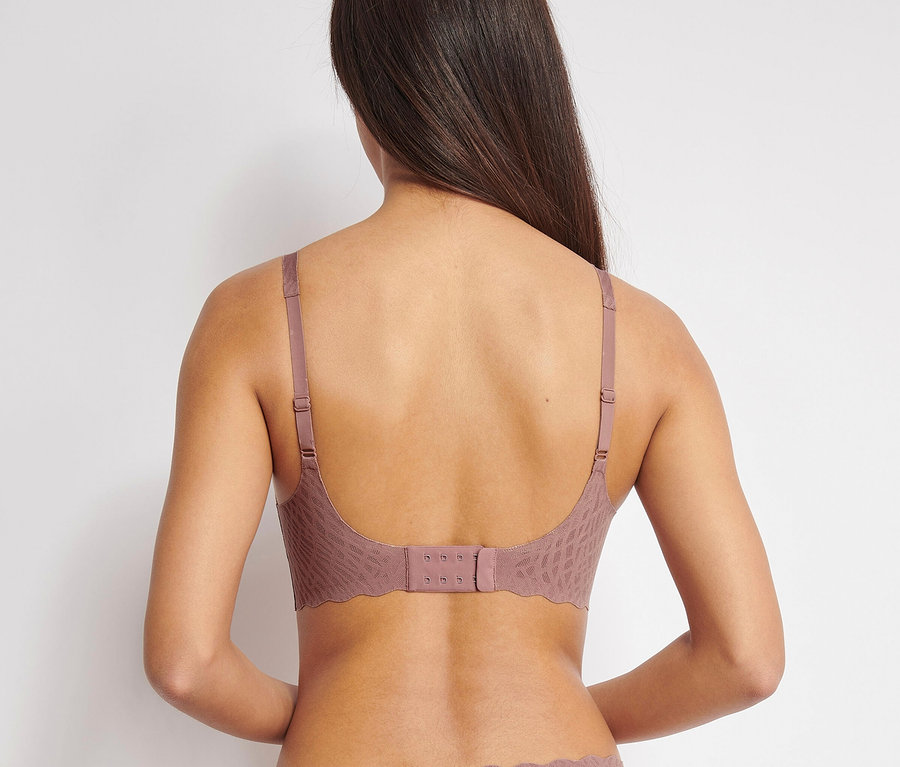 Rückansicht einer Frau mit braunen Haaren, die einen sloggi ZERO Feel Bliss Soft Bra in Kakao trägt.