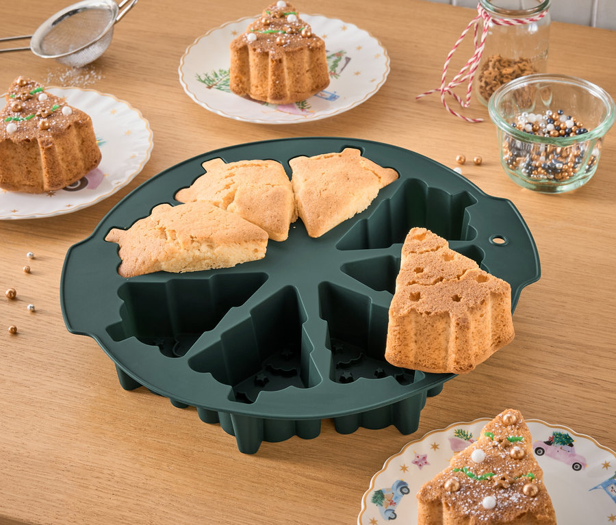 Backform in Form eines Weihnachtsbaums mit gebackenen Kuchen und verzierten Kuchen auf Tellern.