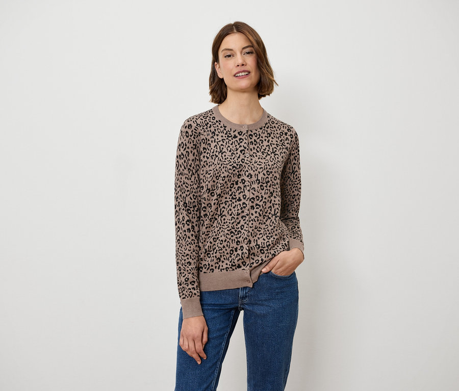 Frau posiert in einem braunen Pullover mit Tiermuster und blauen Jeans.
