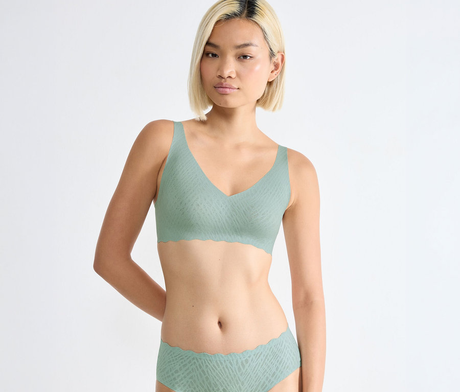 Frau trägt nebel-türkisen sloggi ZERO Feel Bliss Soft Bra und passende Slips mit dezentem Muster und Wellenkanten.
