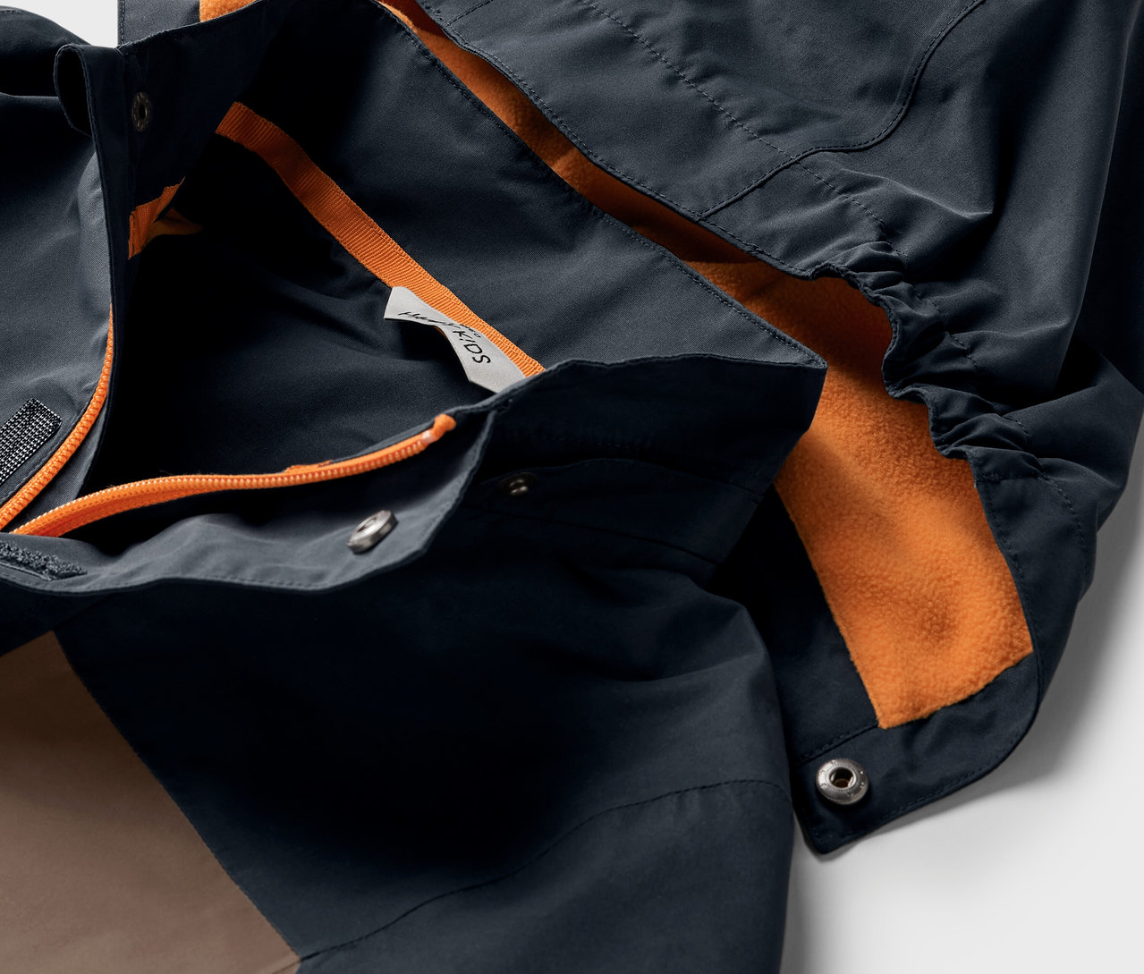 Detailaufnahme einer Kinder-Allwetterjacke mit Kapuze und orangefarbenem Futter.