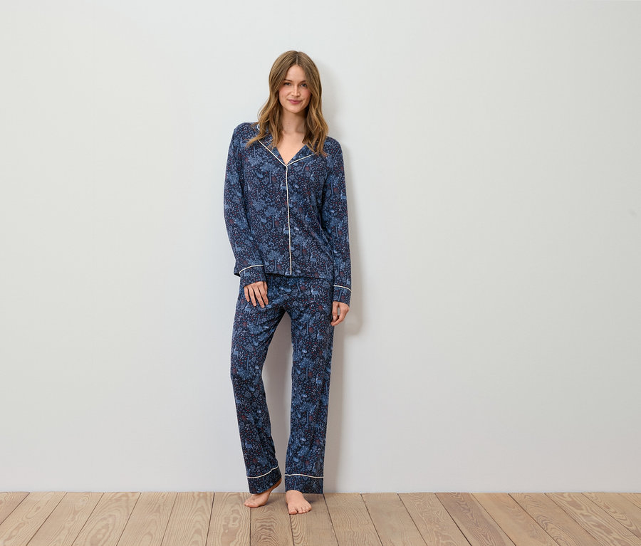 Eine Frau steht und trägt einen blauen Pyjama mit Muster.