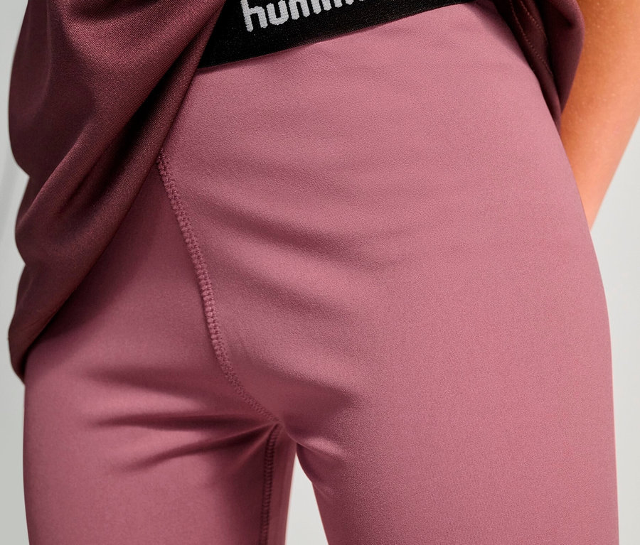 Detailaufnahme von Sportbekleidung, insbesondere einer dunkelrosa Leggings mit schwarzem Hummel-Bund und einem weinroten T-Shirt.