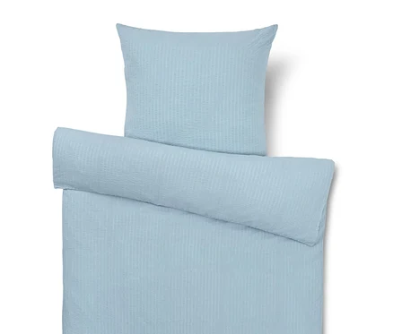 Hellblaue Bettwäsche mit Kissen, Bettdecke und Rolle.