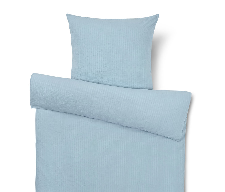 Hellblaue Bettwäsche mit Kissen, Bettdecke und Rolle.