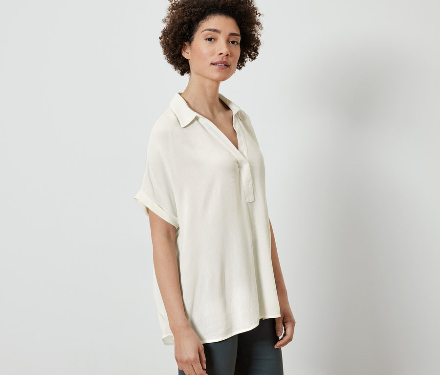 Frau posiert in cremeweißer Bluse.