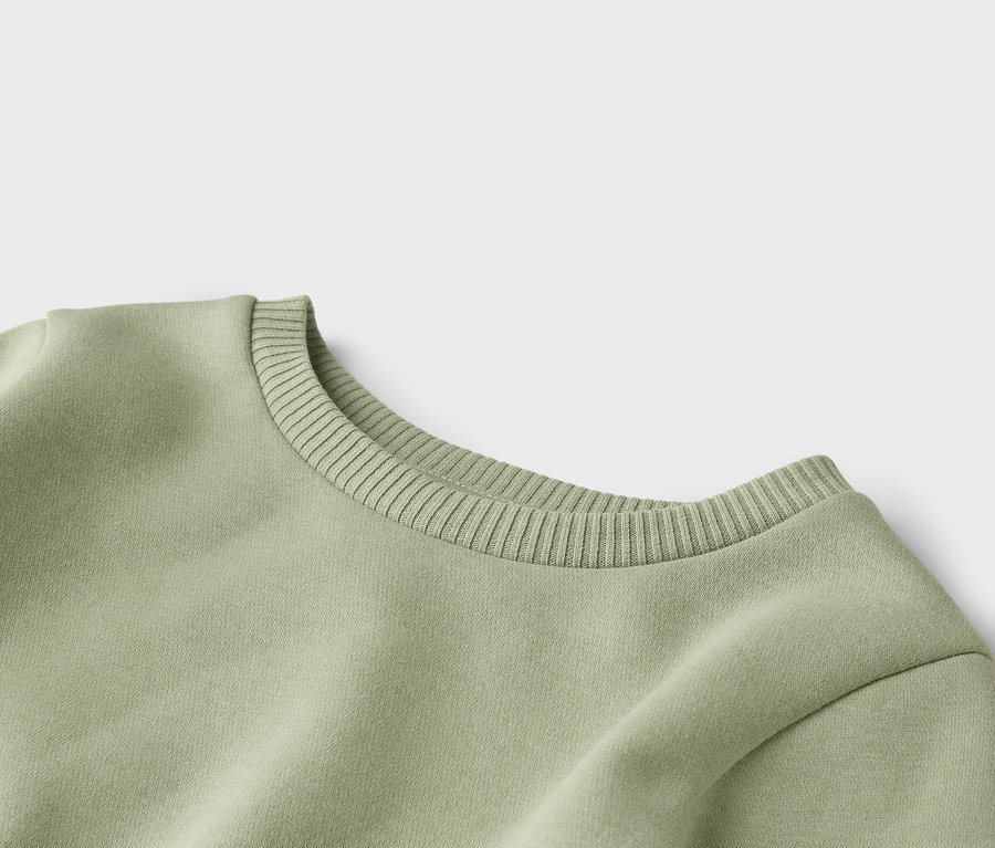 Nahaufnahme vom gerippten Rundhalsausschnitt eines hellgrünen Sweatshirts.