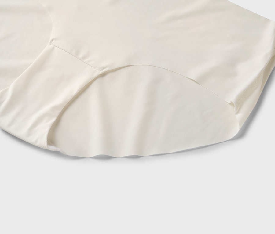 Nahaufnahme eines cremefarbenen Slips auf hellgrauem Hintergrund.