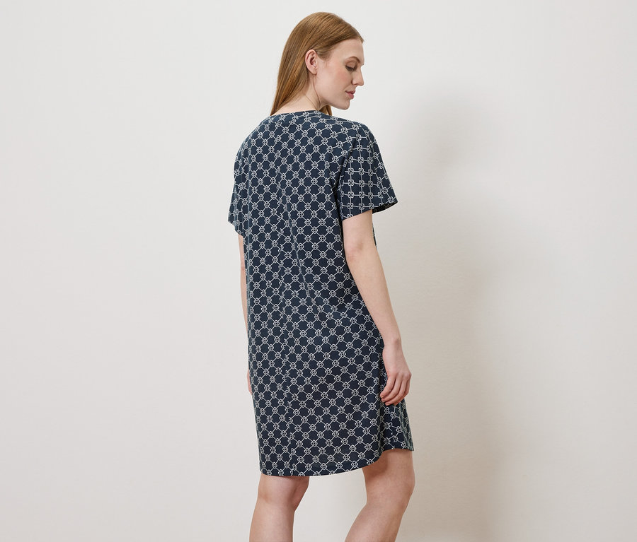 Frau von hinten, die ein blaues Kleid mit weißem Muster trägt.