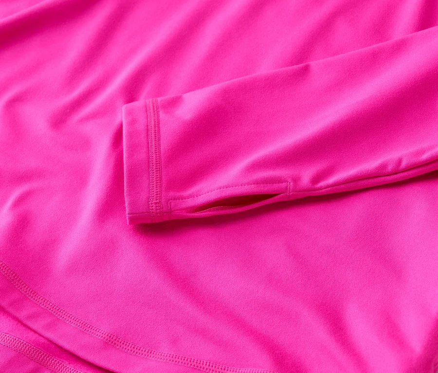 Nahaufnahme eines pinkfarbenen, langärmeligen Oberteils mit Daumenlöchern und doppelt genähtem Saum.