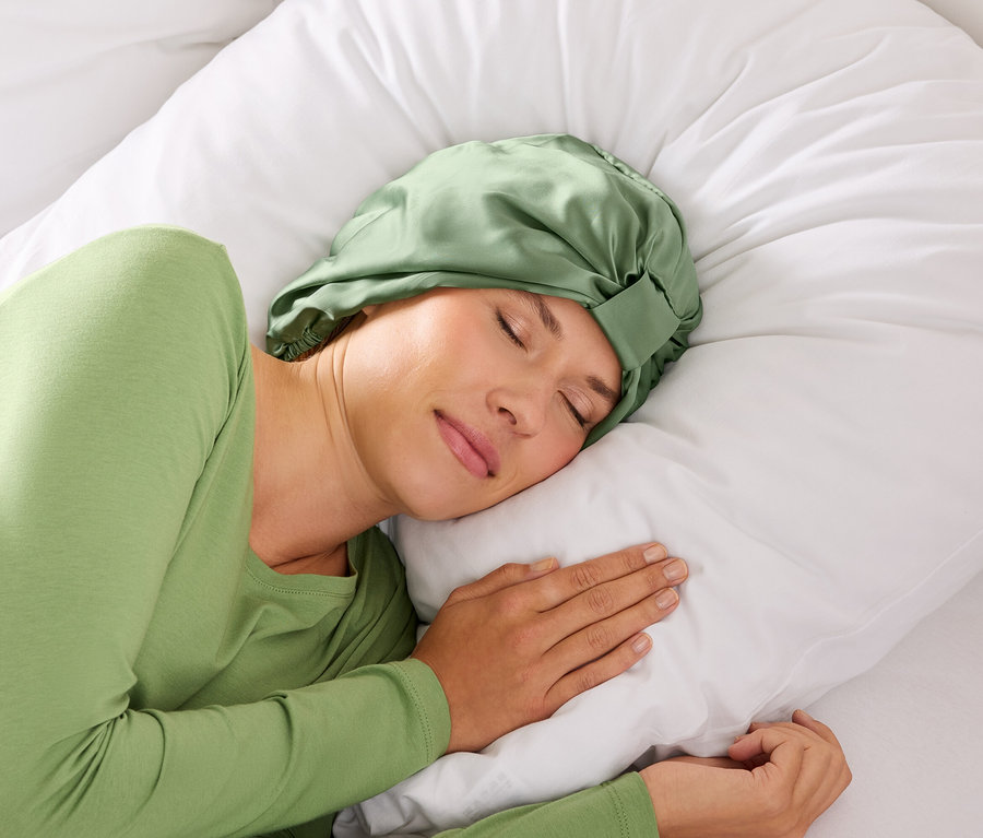 Frau schläft mit grünem Haarband auf einem weißen Kissen.