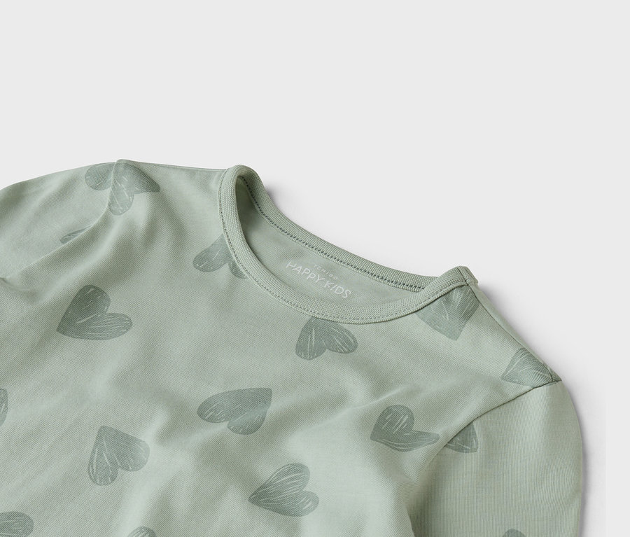 Nahaufnahme eines hellgrünen langärmligen Oberteils mit einem grauen Herzmuster.