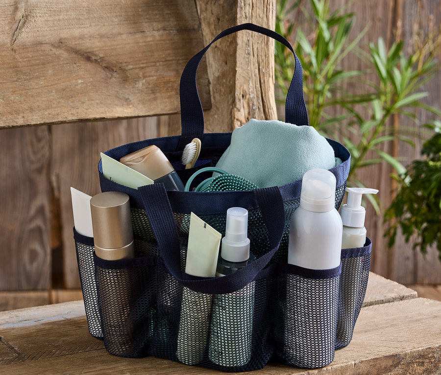 Marineblaue Tragetasche mit Toilettenartikeln auf einer Holzbank.