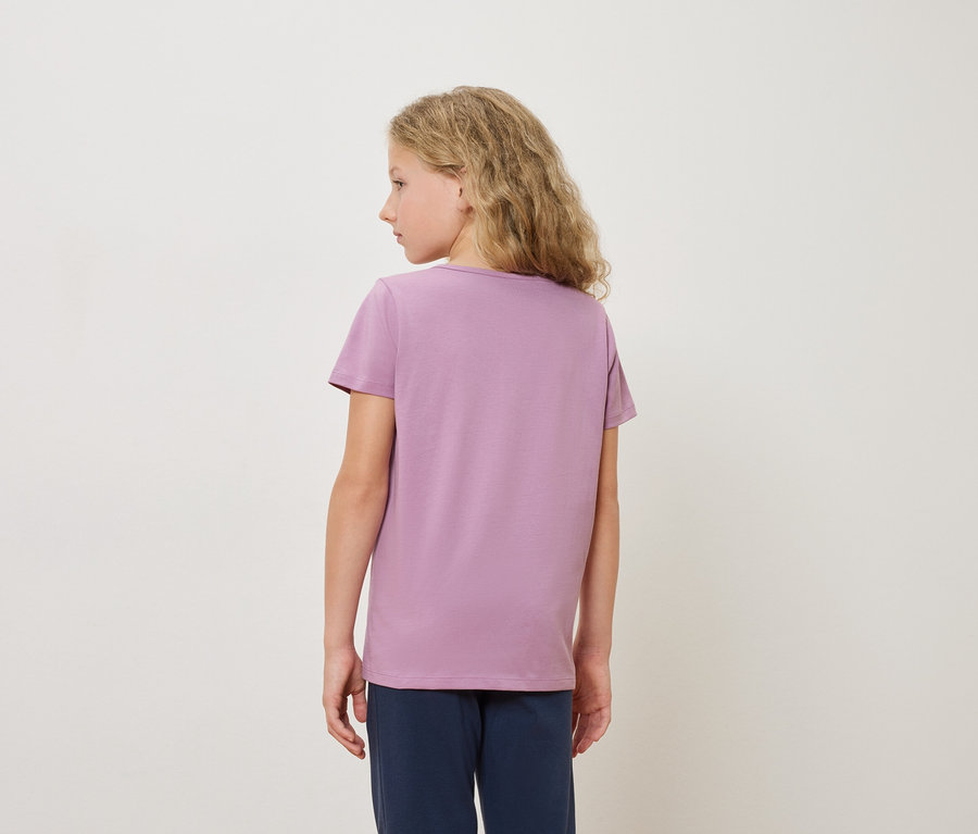 Rückansicht eines blonden Mädchens mit lila T-Shirt und blauer Hose vor einem weißen Hintergrund.