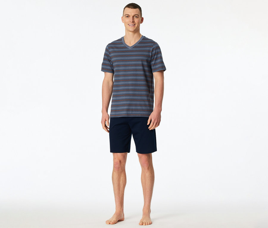 Ein lächelnder Mann steht barfuß und trägt ein gestreiftes SCHIESSER Shorty-Set mit V-Ausschnitt-Oberteil und marineblauen Shorts.