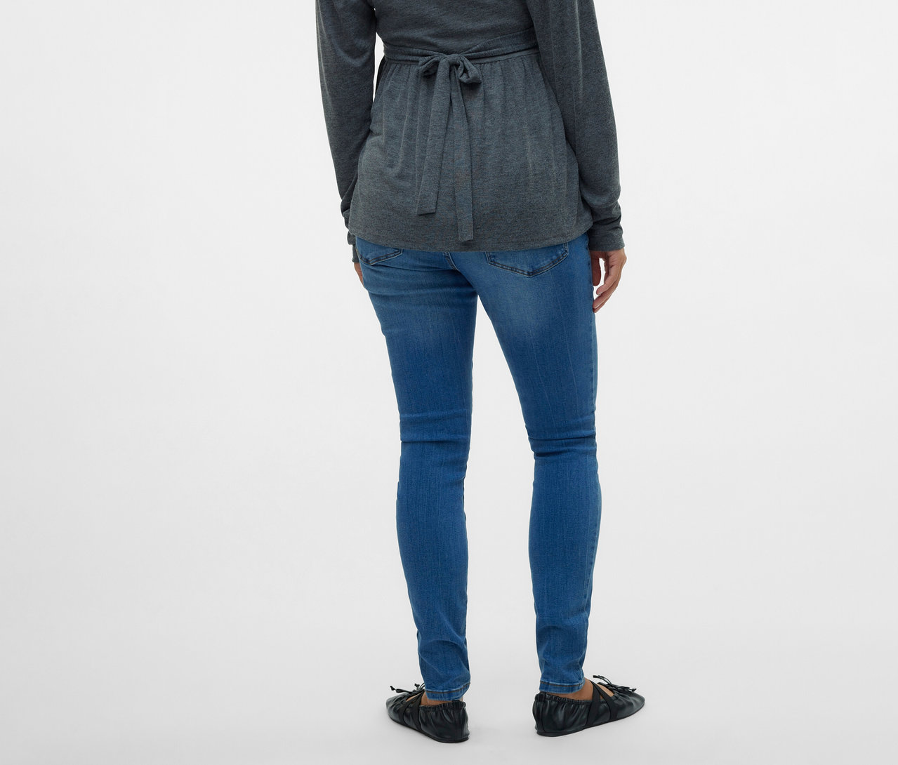 Rückansicht einer Frau mit grauer Wickelbluse und MAMALICIOUS Skinnyjeans »MLMILA« vor einem weißen Hintergrund.