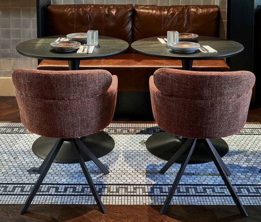 Zwei »Fenne« Stühle im 2er-Set von WOOOD in Kastanienbraun stehen vor zwei Tischen mit Gedecken in einem Restaurant.