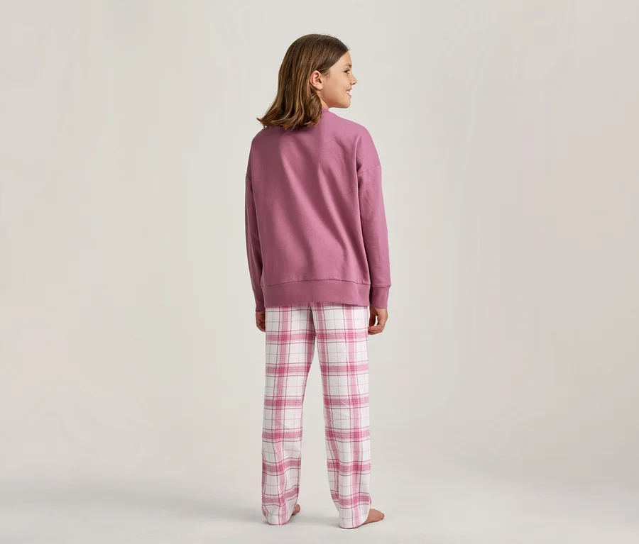 Mädchen von hinten, in einem rosa Sweatshirt und rosa-weiß karierten Pyjamahosen, blickt nach rechts.