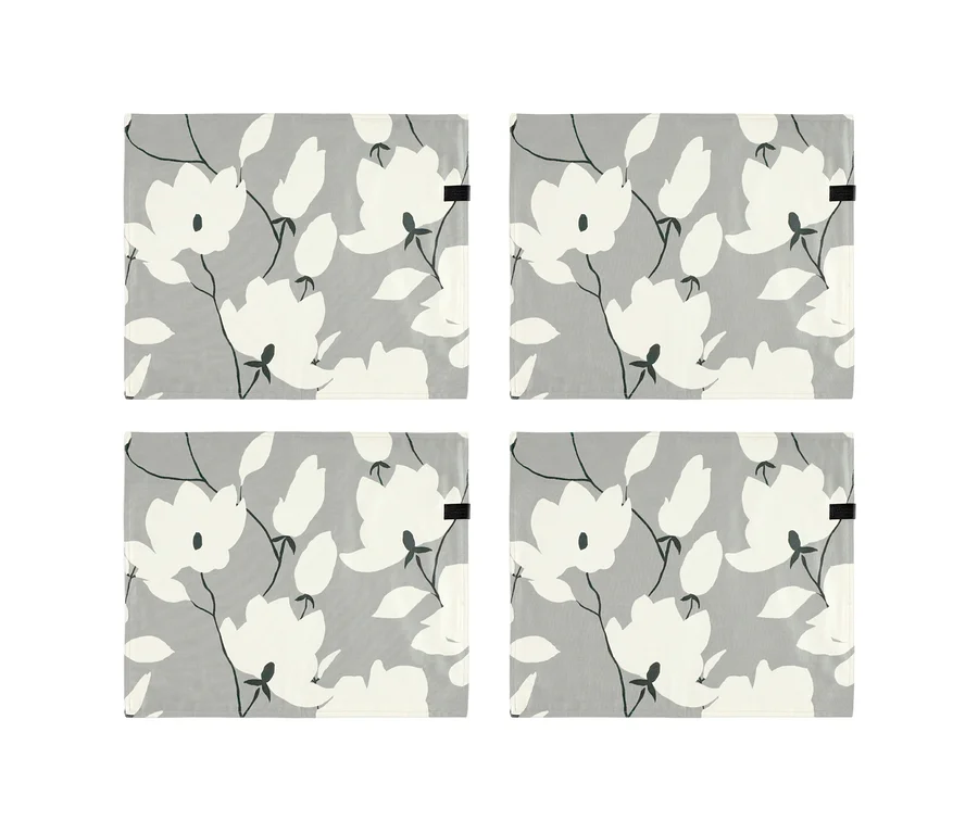 Vier graue, florale Tischsets der SCHÖNER WOHNEN Kollektion mit weißen Blumen und Blättern auf hellgrauem Hintergrund.