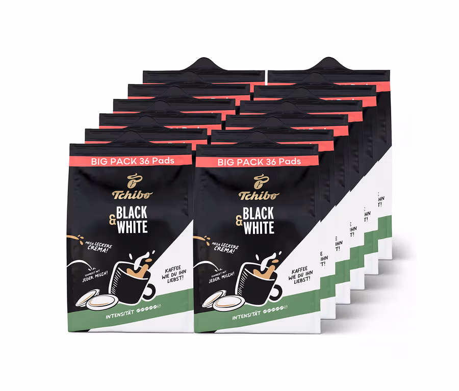 Zwölf schwarze und grüne Tchibo BLACK & WHITE Pads Großpackungen, jede mit 36 Kaffeepads, sind in Reihen gestapelt.