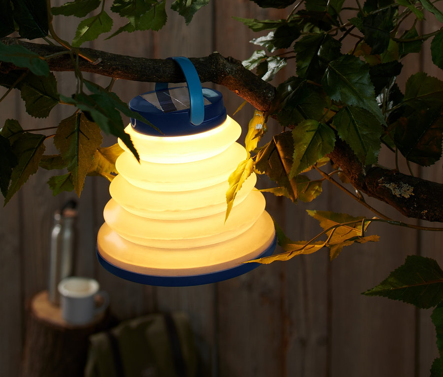 Ein leuchtender, faltbarer Lampion mit USB hängt an einem Ast.