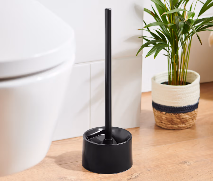 Eine schwarze Silikon-WC-Bürste steht neben einer weißen Toilette.