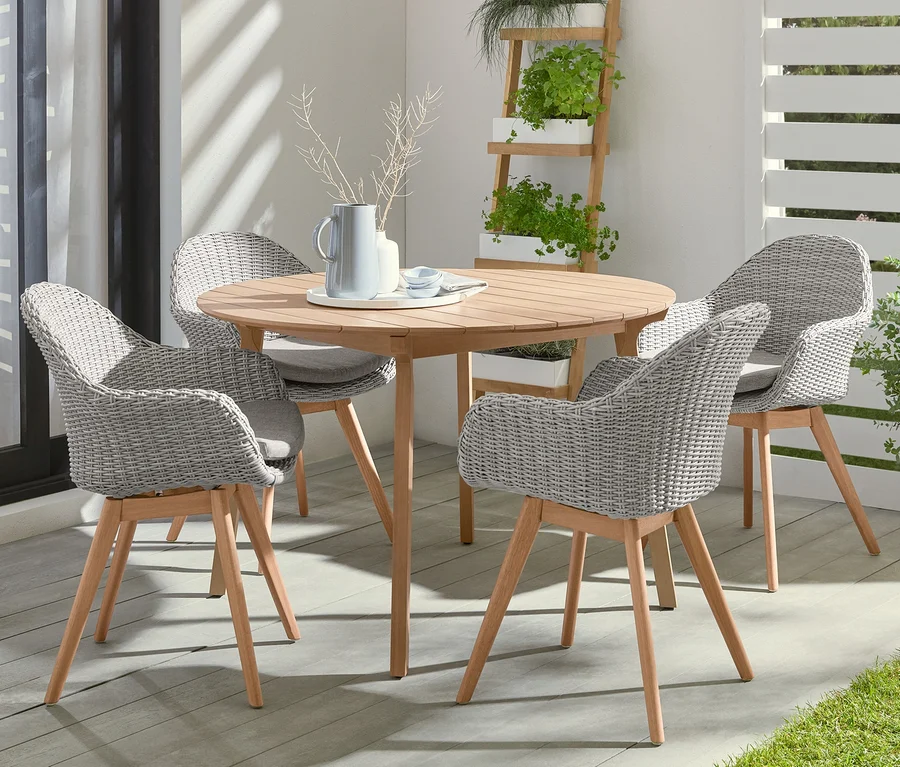 Vier Schalenstühle mit Polyrattangeflecht umgeben einen runden Tisch. Im Hintergrund steht eine LED-Akku-Stehleuchte.
