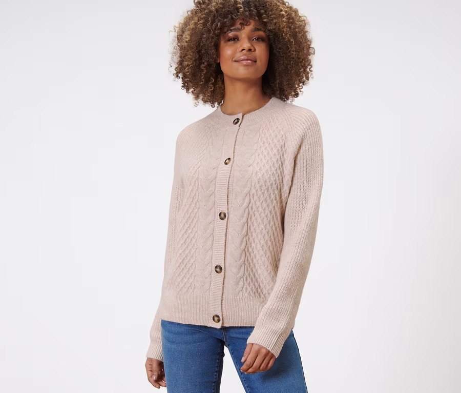 Frau trägt einen Strickcardigan mit Zopfmuster und Jeans.
