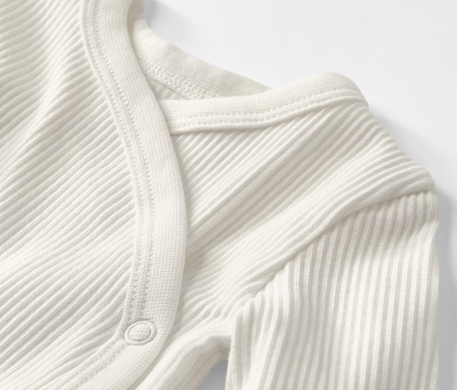 Detailansicht eines weißen Baby-Ripp-Langarmbodys.