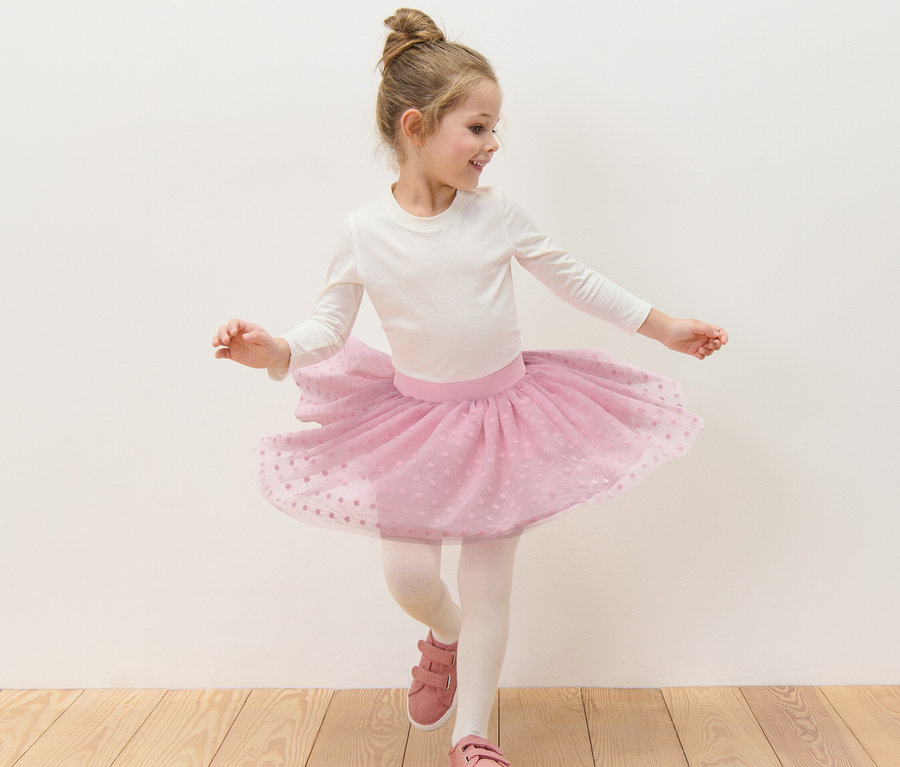 Mädchen tanzt in weißem Oberteil und rosa Kinder-Tüllrock.