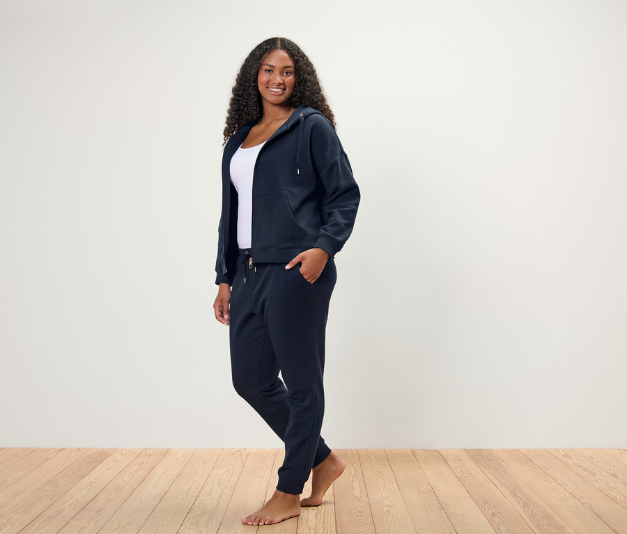 Frau steht und posiert in einem dunkelblauen Hausanzug.