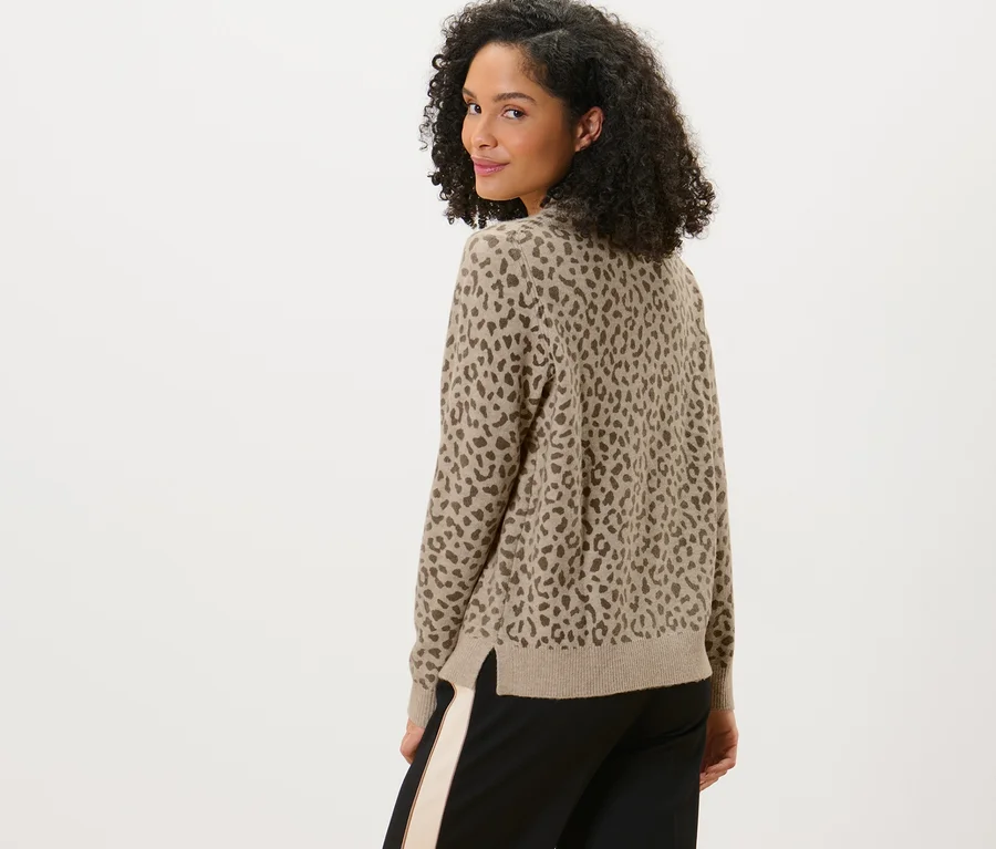 Frau blickt über die Schulter und trägt einen bedruckten Strickpullover.