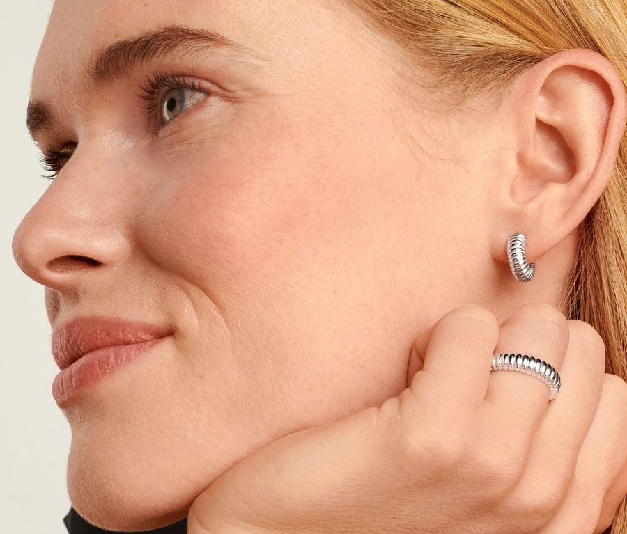 Blonde Frau trägt 925 Silber Creolen Ribbed und 925 Silber Ring Ribbed.