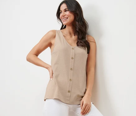 Lächelnde Frau posiert in beige meliertem Top mit Knopfleiste und weisser Hose.