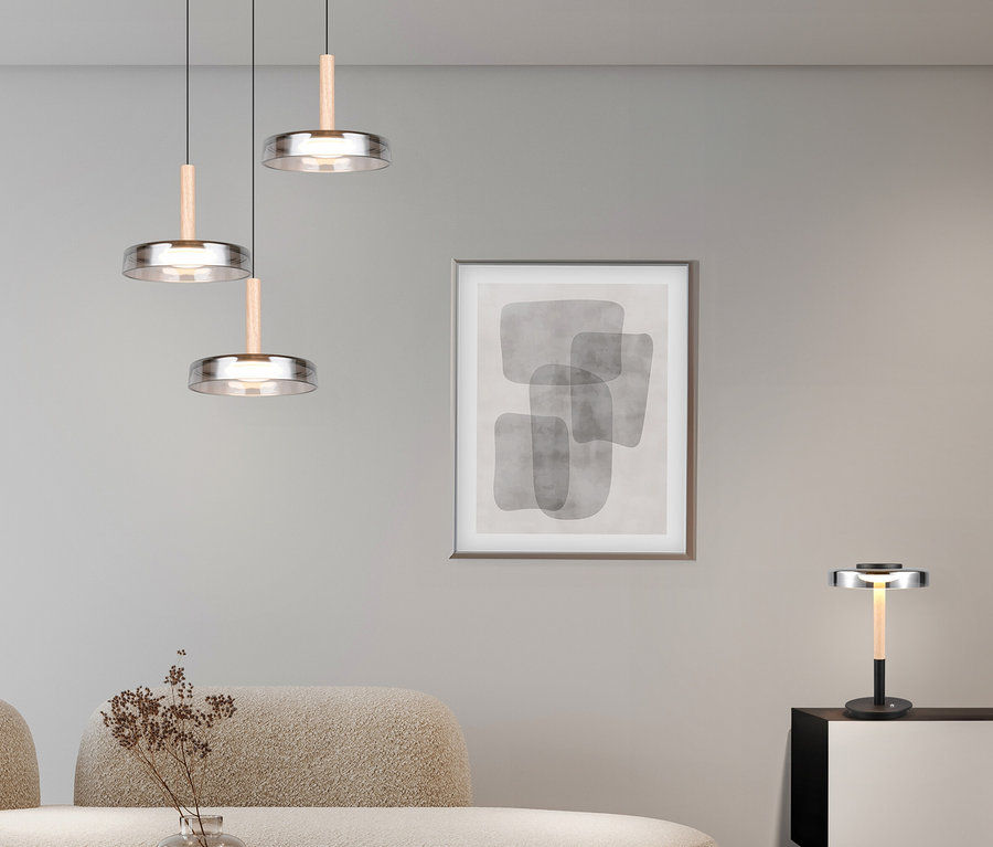 Wohnzimmer mit beigem Sofa, Couchtisch und Wandkunst. Drei Trio LED-Pendelleuchten »Celeste« hängen über dem Tisch, eine Trio LED-Tischleuchte »Celeste« steht auf einem Schrank.